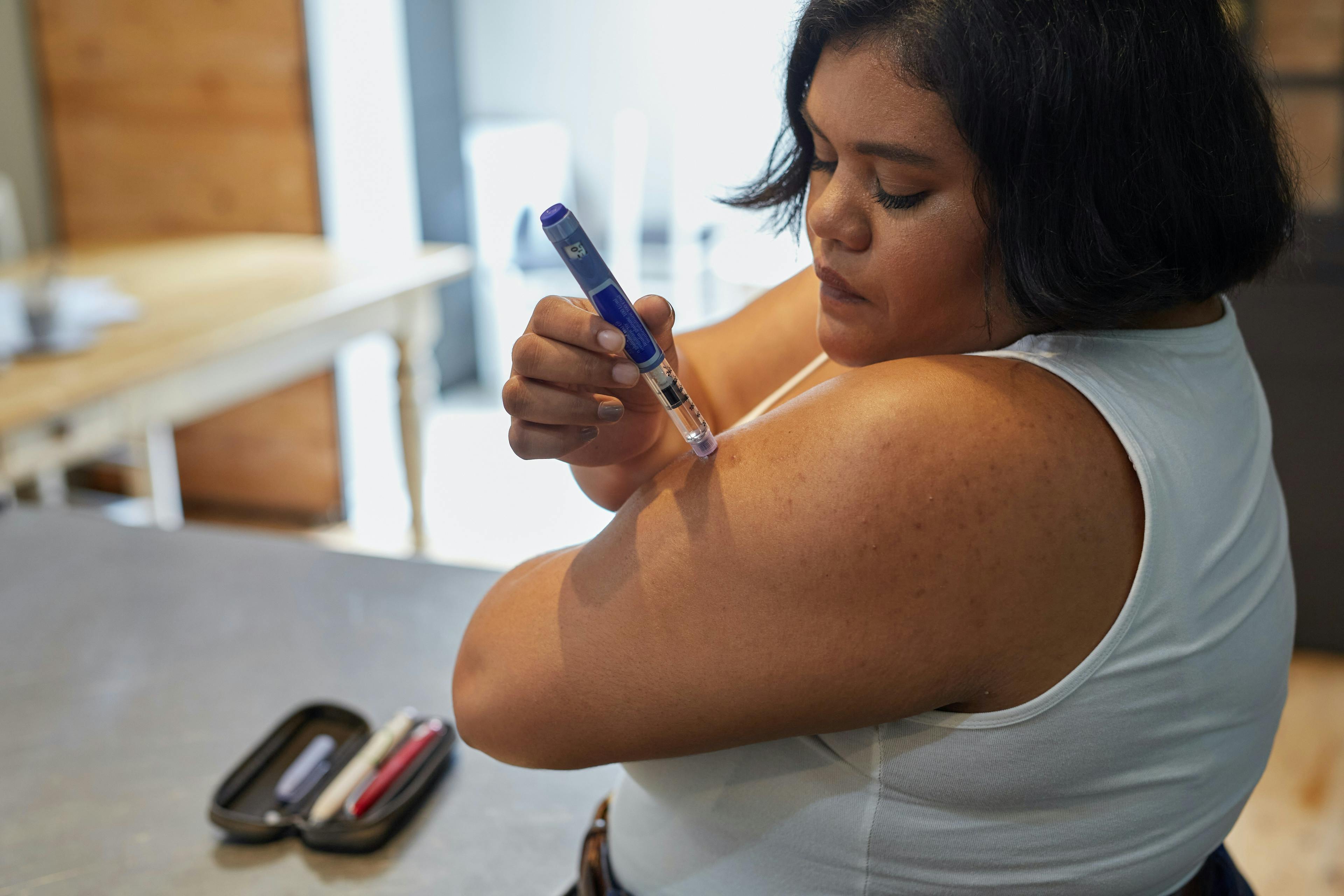 Young South African woman taking insulin for Type 1 diabetes with an insulin injection pen.