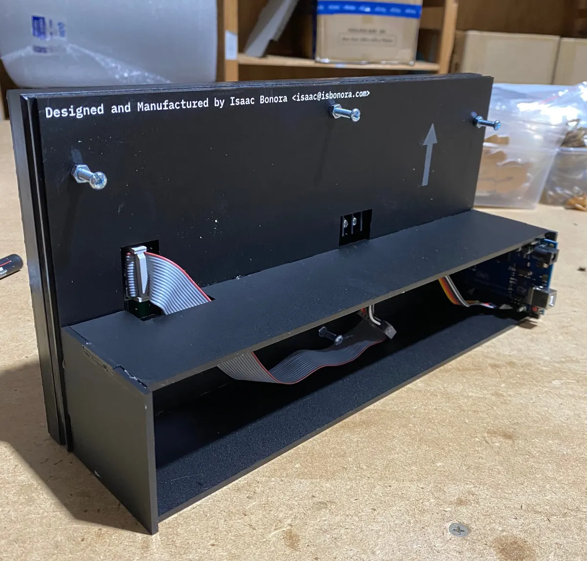 Rear of the laser-cut black display case with ribbon cable and Arduino board inside
