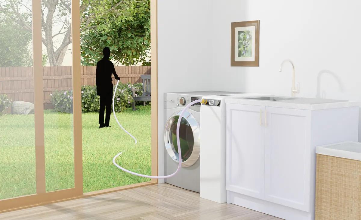 Render of the Grey Cycle beside a washing machine, its hose running outside to water the garden